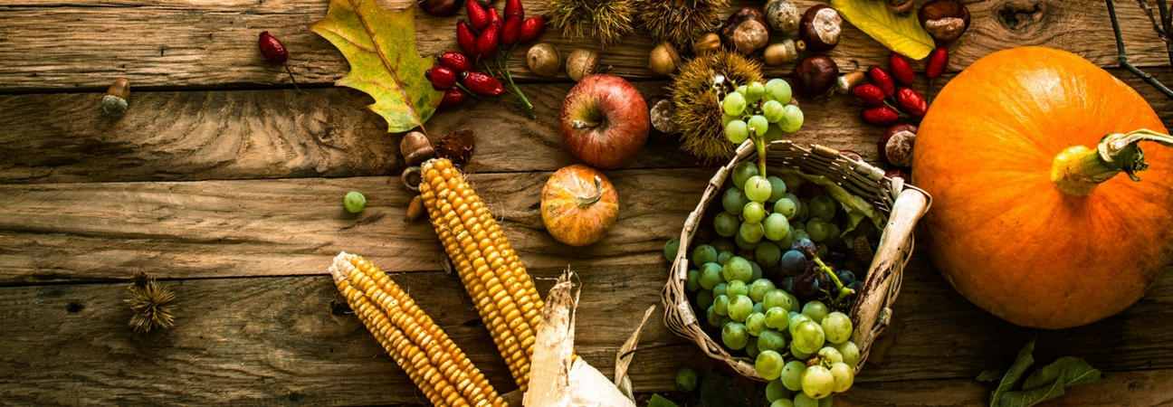 A table with a pumpkin, corn, and other food featured in a blog about Thanksgiving traditions