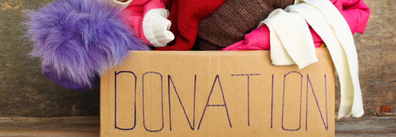 Cardboard Donations box filled with sweaters and scarves.