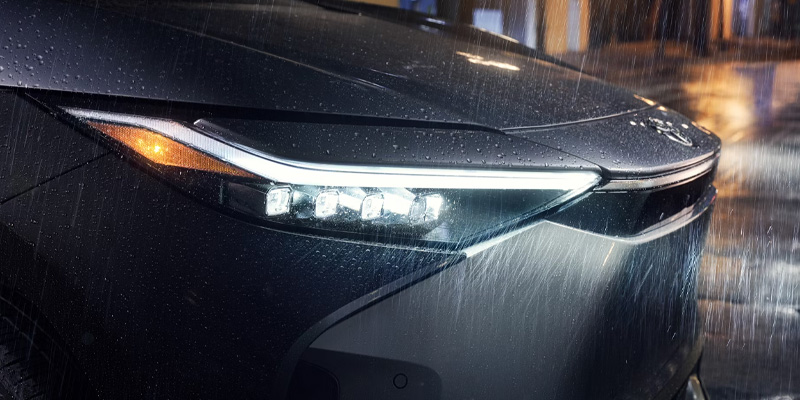 The headlight of a 2025 Toyota bZ4X illuminating the rain in Ardmore, PA