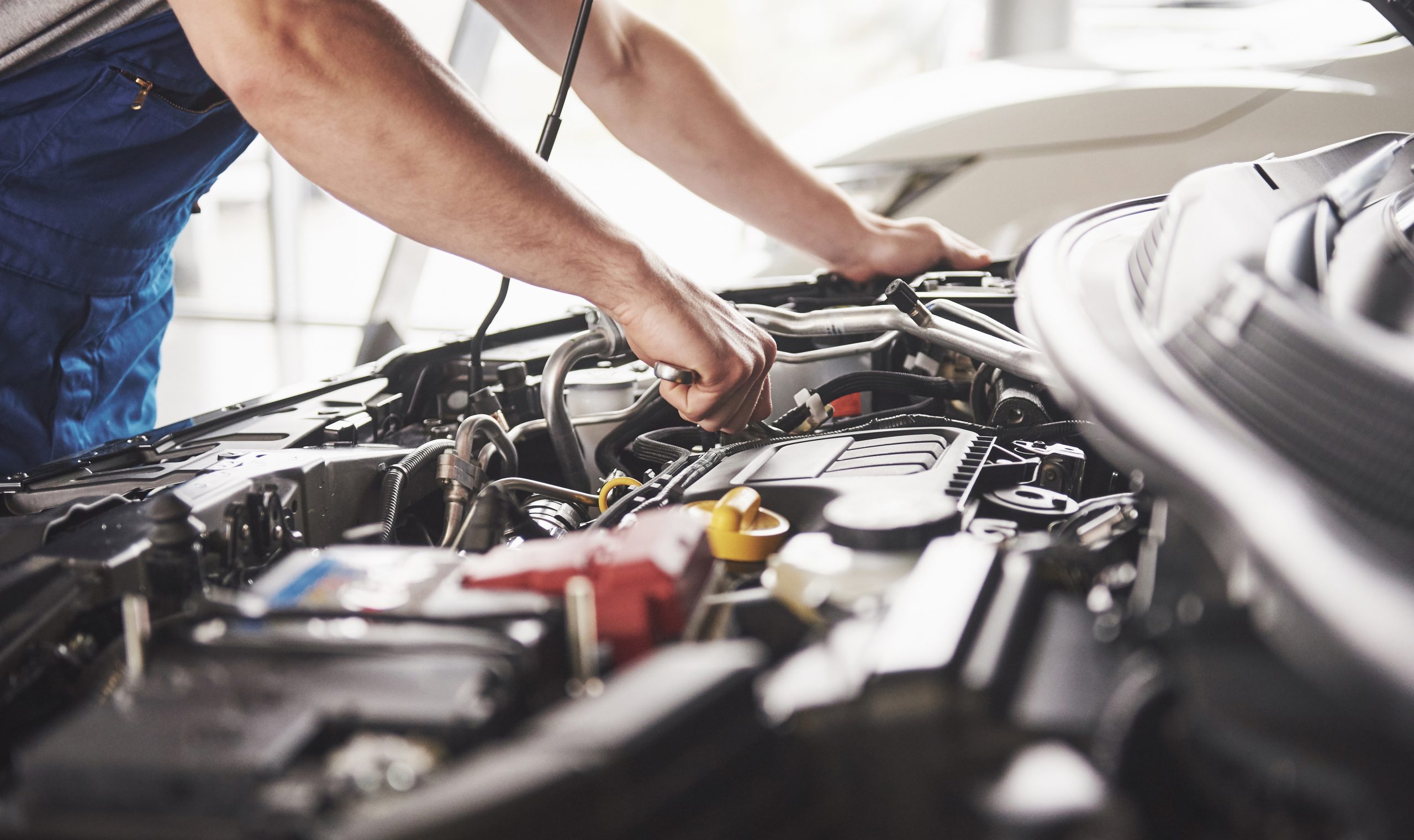 Mechanic inspecting vehicle engine components under hood